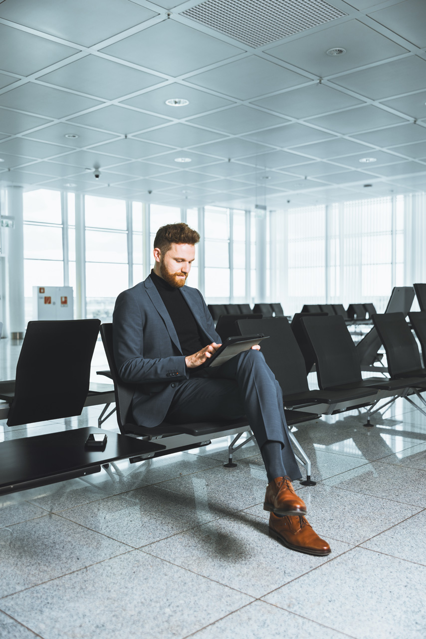 Sitzender Businessman am Flughafen München, professionell ausgeleuchtet für die Business-Fotografie.